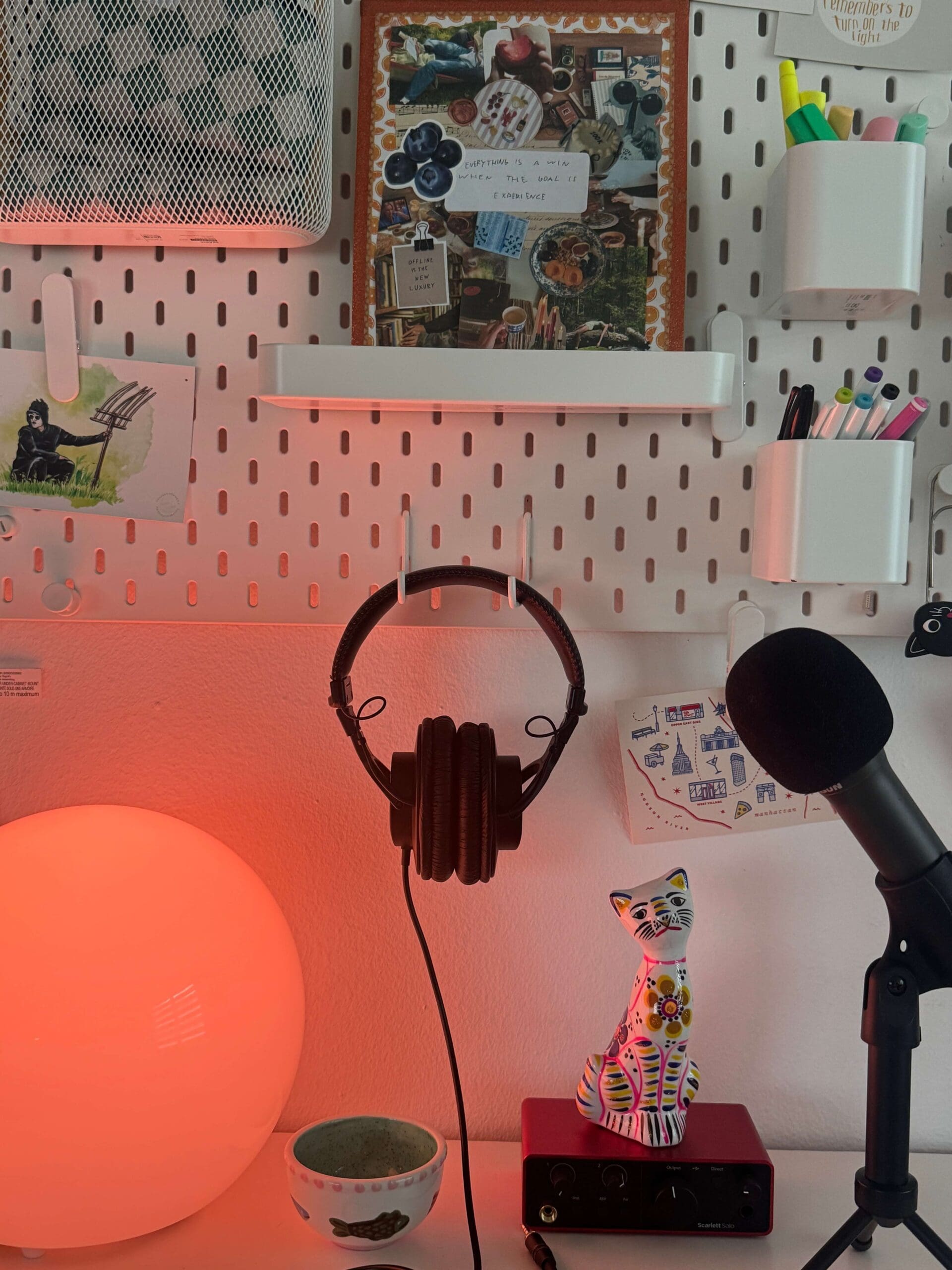 This setup features essential podcasting gear, such as headphones and a microphone, mounted on an organized pegboard wall.